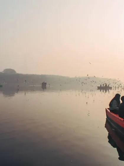 A wider view of the Yamuna, showing several boats on the water. This image gives a sense of the community and shared experience of being at the ghat in the early morning.