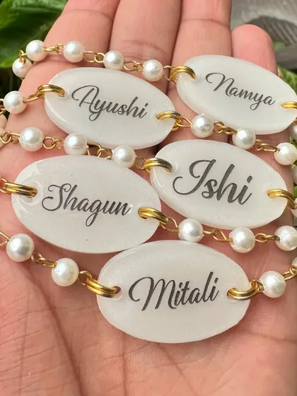 A collection of personalized rakhi bracelets held in hand, showing different names in elegant script. These can be worn long after the festival.