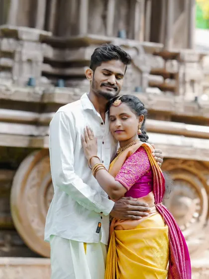 An intimate embrace during a pre-wedding shoot, with a traditional temple chariot wheel in the background.