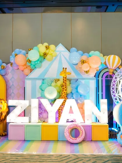 An adorable pastel carnival photo stage for a 5th birthday, featuring a light-up ferris wheel, animal props, and the birthday boy's name in giant letters.