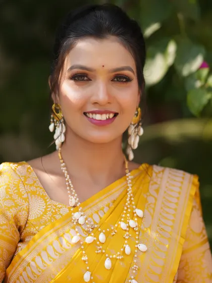 A close-up portrait of the Haldi bride, focusing on her flawless, dewy makeup and bright smile.