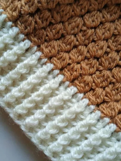 A close-up view of the textures on the Flora beanie. You can see the puffy cluster stitches of the main hat body next to the tight front-post stitches of the brim.
