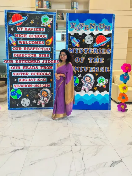 Posing next to the beautifully decorated welcome boards at St. Xavier's High School. The theme for the event was 'Mysteries of the Universe,' and the students' creativity was out of this world.