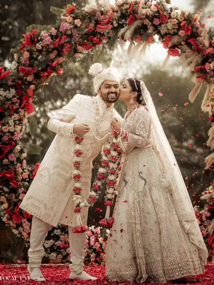 A sweet kiss on the cheek under a beautiful floral arch. We capture the spontaneous displays of affection that make your wedding photos feel personal and real.