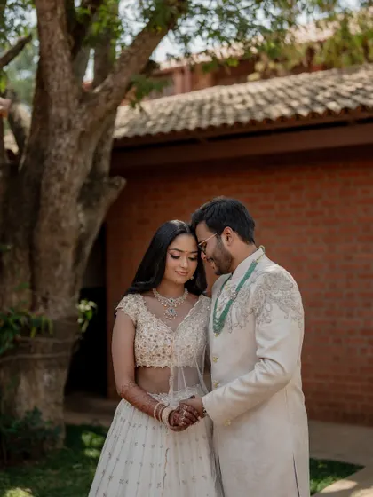 An intimate portrait of the couple in their elegant white and green themed engagement attire, set against the natural backdrop of the venue.