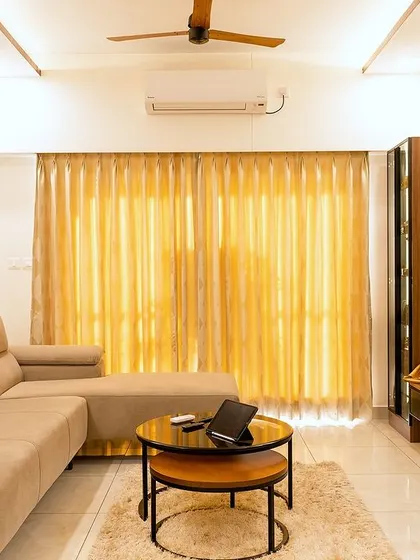 The living room in the Murlis' home showcases a refined harmony of textures and tones, with a comfortable sectional, a sleek TV unit, and warm lighting creating a welcoming atmosphere.