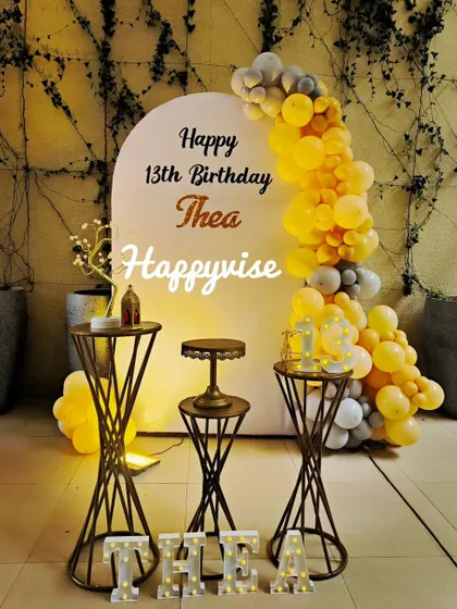 A stylish 13th birthday celebration for Thea. The yellow and grey balloon arrangement against a simple white arch creates a modern and trendy vibe perfect for a teenager.