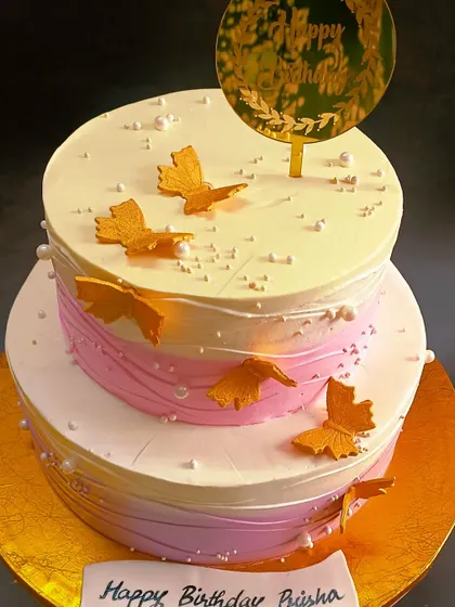 An elegant two-tiered cake with soft ombre colours and delicate golden butterflies.