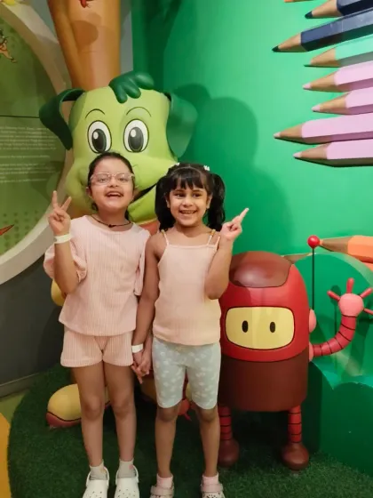Best friends make the best memories. Two girls hold hands and flash peace signs while posing with our mascots.