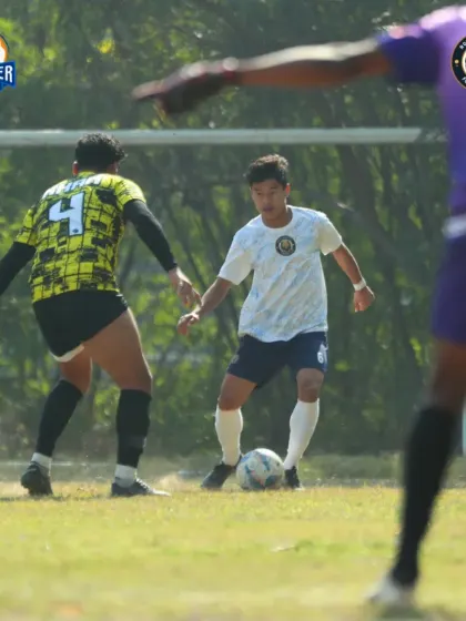 A player dribbles with close control, navigating through a tight space on the pitch.