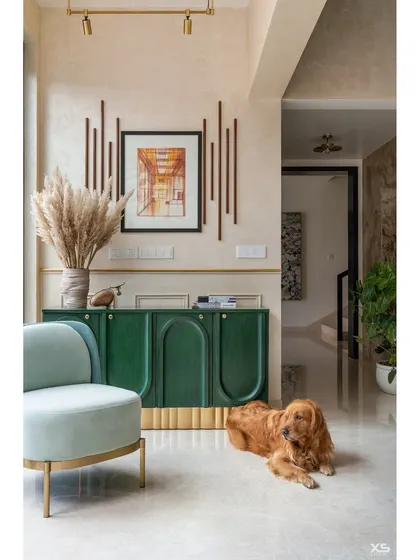 A custom-designed green credenza with arched details and brass accents serves as a stylish storage solution in the foyer. The space is calm and welcoming, with our client's dog, Bruno, often found lounging here.
