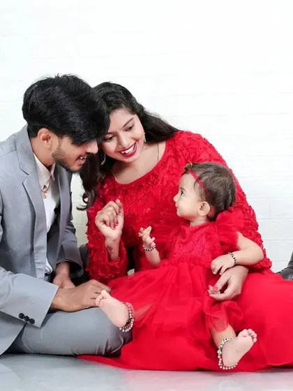 A beautiful family portrait with everyone dressed in coordinating red outfits. The simple white background allows the family's connection and vibrant color choice to stand out.