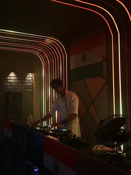 A photo of me at the decks at Drunken Daddy, with the Indian flag in the background for our Independence Day celebration.