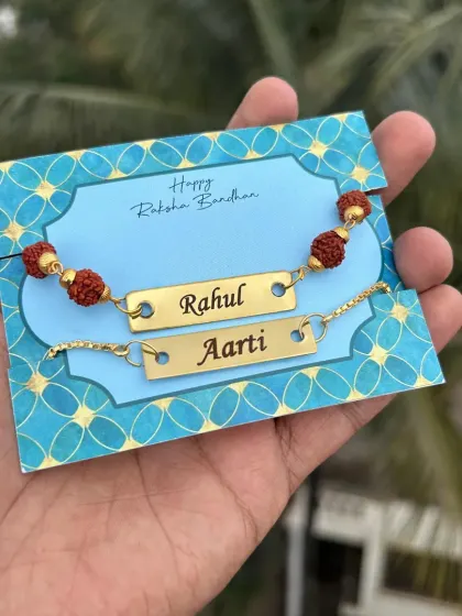 A simple and elegant rakhi set for a brother and sister, featuring matching nameplates on a traditional rudraksh thread.