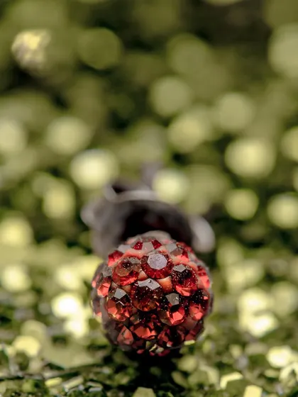 An abstract macro shot of a red, jeweled object against a bokeh background. The focus is purely on color, light, and texture.