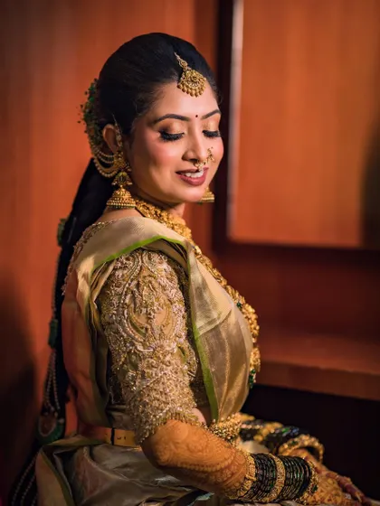 A side profile of the bride, showcasing the intricate details of her gold blouse and traditional jewelry.