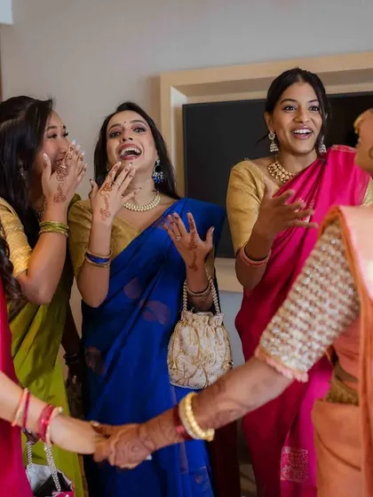 The bride and her bridesmaids share a laugh and hold hands, a beautiful moment of friendship and support.