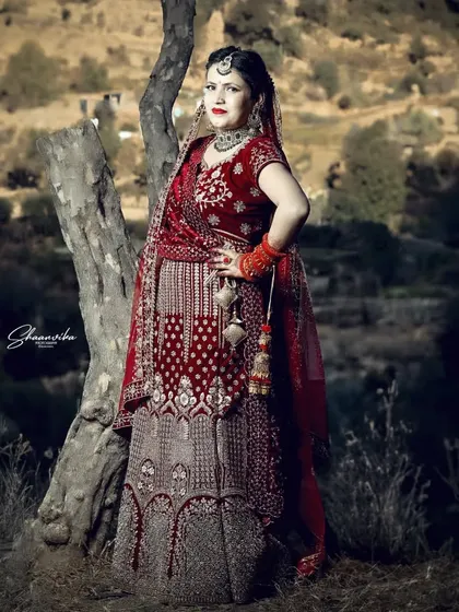 A full-length outdoor portrait of the bride, showing how the traditional attire looks against the rustic Himachali landscape.