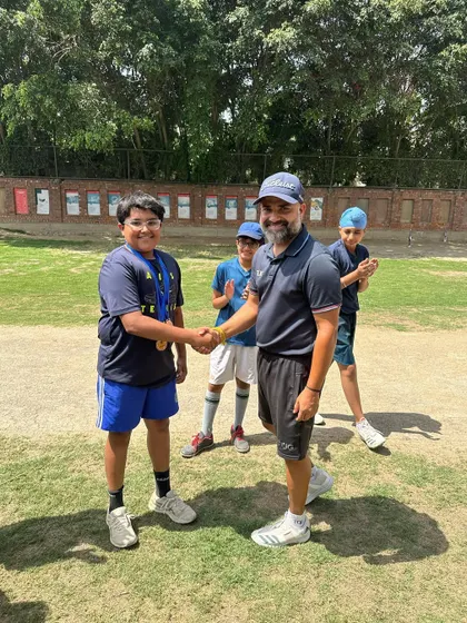 A young player smiles as he receives his medal from the coach. Celebrating achievements is a core part of our academy's culture.