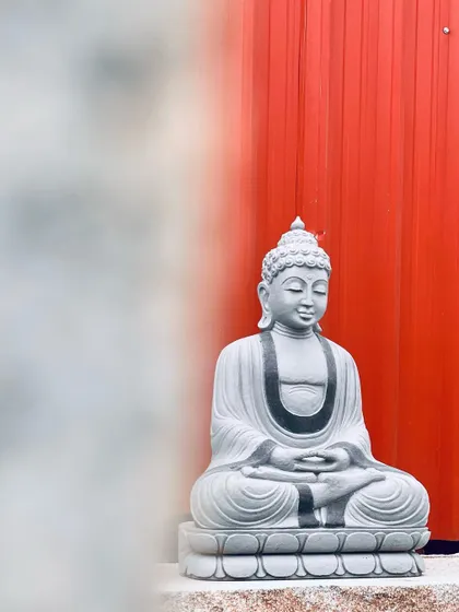 An artistic shot of a stone Buddha statue against a red background, creating a striking contrast.