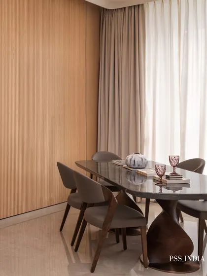 Every detail on the table tells a story. This modern dining set, with its sculptural base and sleek chairs, is styled with colorful glassware and a simple vase, making every meal feel memorable.