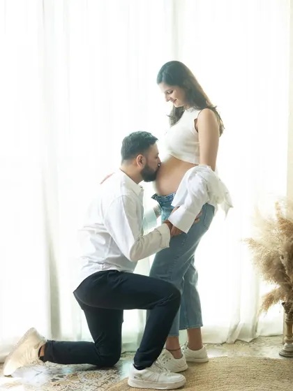 A kiss for the baby. This is such a loving and classic pose for a couple's maternity shoot, filled with anticipation for the little one's arrival.