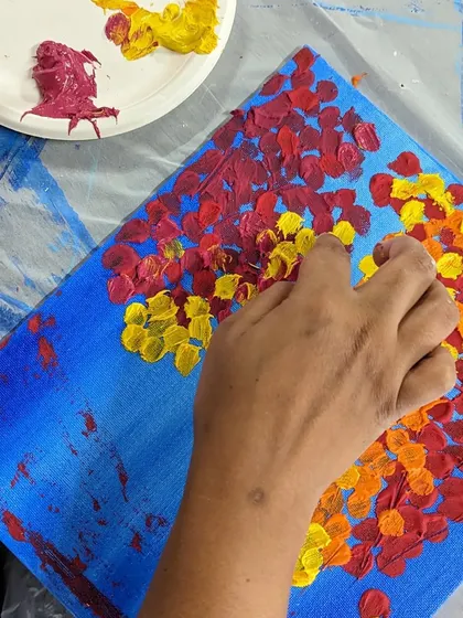 Using fingers to create a textured, impasto effect for flowers on a canvas. It's a fun and intuitive way to connect with your art.