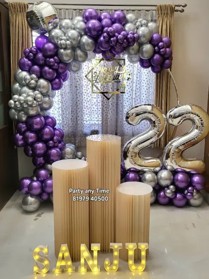 A stylish 22nd birthday decoration with a purple and silver chrome balloon arch, large foil numbers, and light-up letters.