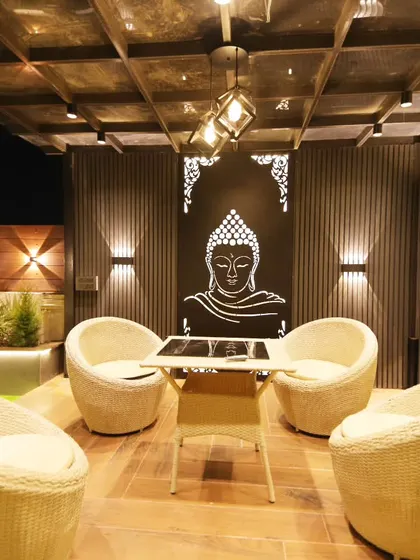 A close-up of the seating arrangement under the pergola in Sushant Lok, highlighting the intricate wall panels and lighting.