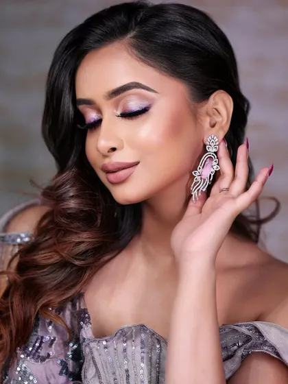 A side profile highlighting the dramatic earrings and the pop of color from the eye makeup. This demonstrates how to create a balanced look where the makeup complements the accessories.