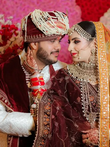 A beautiful portrait of the couple looking at each other. This shot captures the love and connection between them on their wedding day, set against a colorful floral wall.