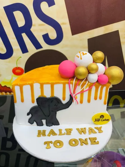 A 1.5kg half-birthday cake with an elephant silhouette and a cascade of colorful balloons.