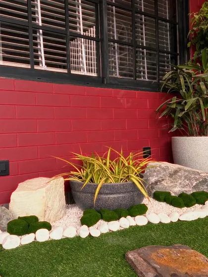 A detail shot of the rock and pebble border, which defines the edge of the artificial lawn and adds a natural, rustic texture.