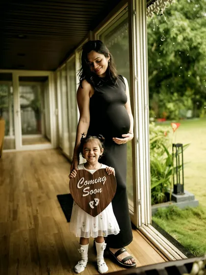 A beautiful full-length portrait of a mother and daughter sharing their happy news. The daughter's proud smile as she holds the announcement sign is a precious memory.