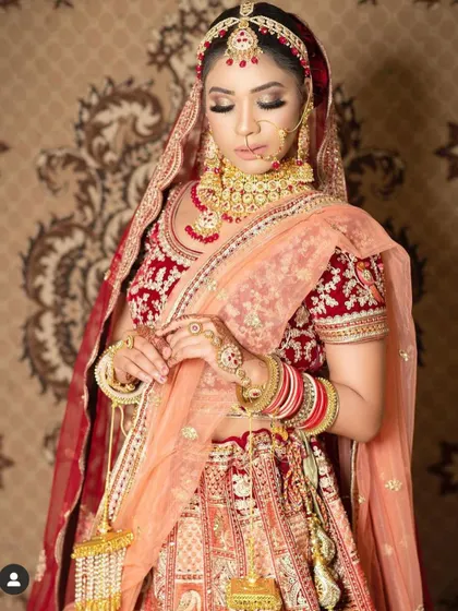 This bride is wearing a traditional red and gold Kundan set with a matching sheesh patti and nath. It’s a classic choice for a reason.