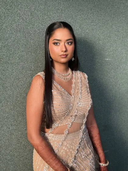 A modern, editorial-style shot. The makeup is kept clean and luminous, allowing the bride's natural beauty and stylish outfit to take center stage.