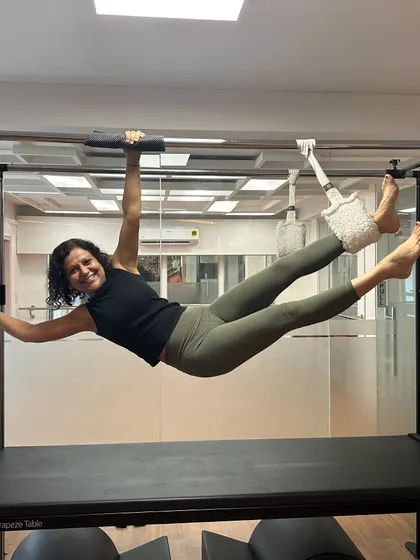 Strength looks good on you. This client is joyfully demonstrating her power and control on the Cadillac, a testament to her consistent hard work and the empowering nature of Pilates.