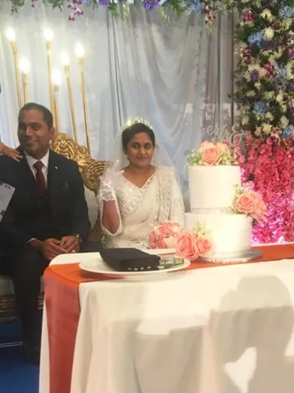 The bride and groom at their reception with the classic three-tier wedding cake I created for them. Even with last-minute orders, I ensure every cake is a worthy centerpiece for such an important occasion.