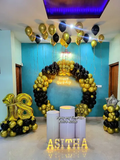 An impressive 18th birthday party setup with a full circular balloon arch in black and gold, a large foil number bouquet, and light-up letters.