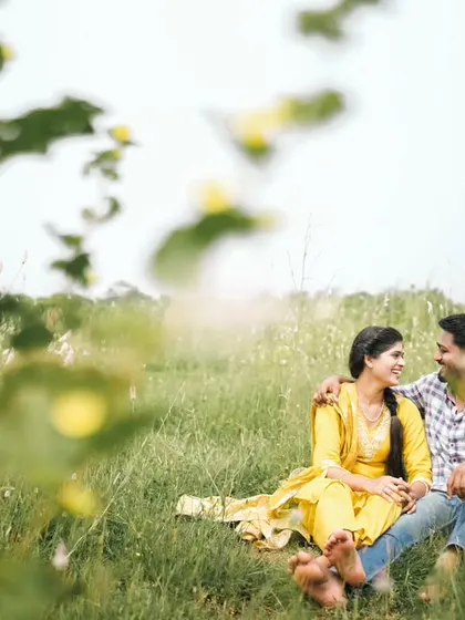 A candid moment of shared smiles in a field, perfectly capturing the joy of being together.