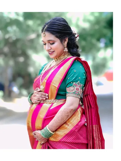 A solo portrait of the mother-to-be, cradling her bump with a gentle smile. Her traditional silk saree and jewelry add to the richness of the Seemantham celebration.