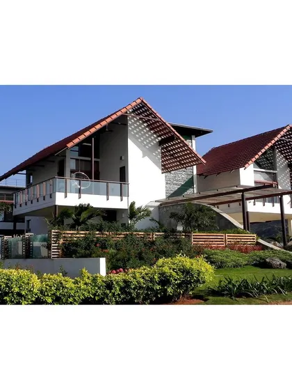 This golf villa in Kovai uses a lightweight steel structure and floating roofs to minimize its footprint on a site with massive natural stone outcrops.