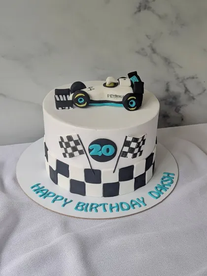 Turning 20 on full throttle! This Formula 1 themed cake features a checkered flag pattern and a handcrafted Mercedes F1 car on top.
