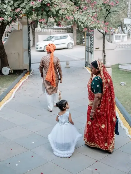 A little flower girl following the groom and his mother. This candid shot captures a sweet, quiet moment from the perspective of the youngest attendee.