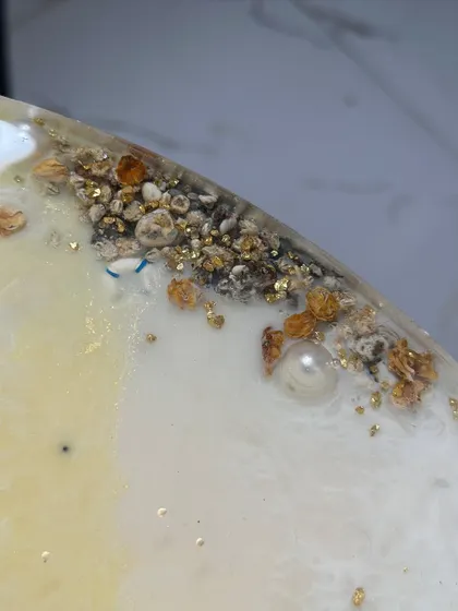 Another close-up of the tabletop, showing the texture of the preserved varmala and sand, with pearls scattered like seafoam.