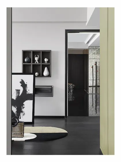 The entry to the 'Reflections' home sets a monochromatic and artistic tone. An abstract painting is propped against the wall, and curated objects sit in a shadow box, creating an interesting composition that welcomes you into the space.