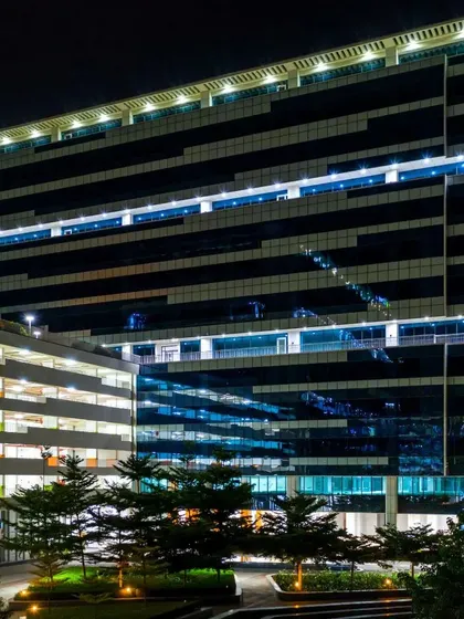 A direct facade shot of a glass-paneled office building at night. This image highlights the building's striking architectural lines and interior lighting.