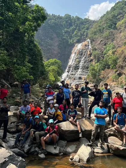 A group photo from a summer trek, with the waterfall in the background. Even in summer, the beauty of these places is undeniable.