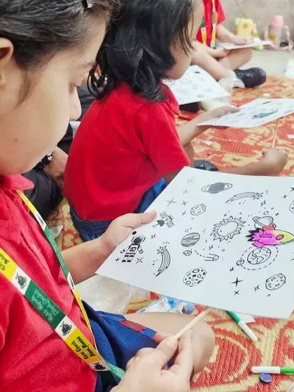 A student colors a space-themed worksheet, a fun introductory activity before building her magnetic rocket ship.