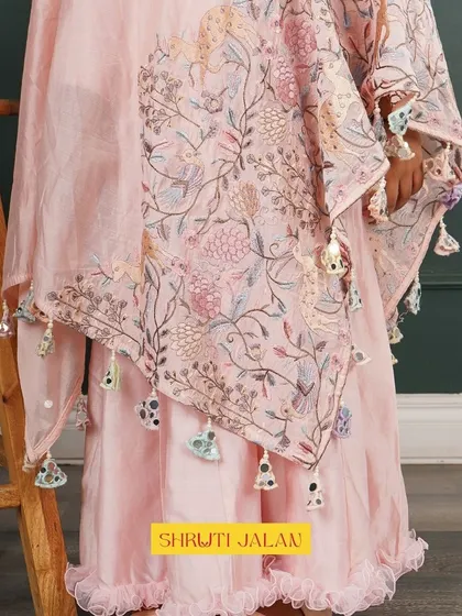 A close-up of the details on my pink cape set. You can see the beautiful floral print on the cape and the playful tassels that add a touch of whimsy to this elegant outfit.